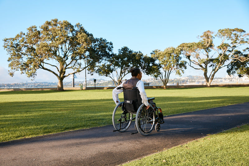 Person in a Karma Wheelchair in park surrounded by grass and trees