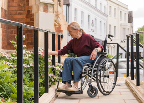 Woman in a wheelchair looking at flowers.