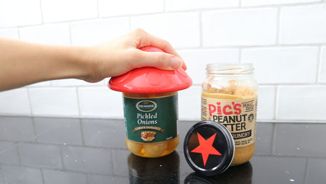 Person using a red jar opener to open a jar