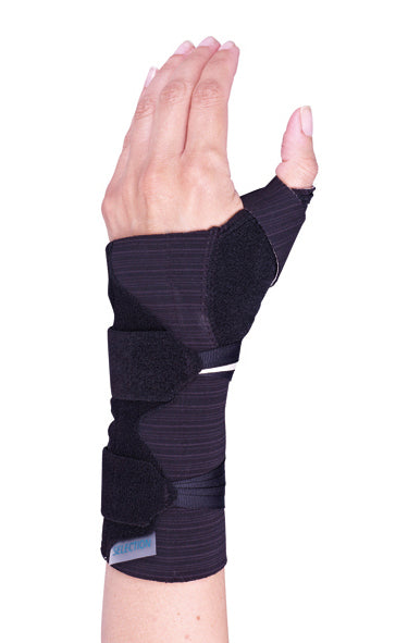 A hand wearing a black wrist and thumb support brace with adjustable straps, designed to stabilize and protect the wrist and thumb. The fingers are free and extended.